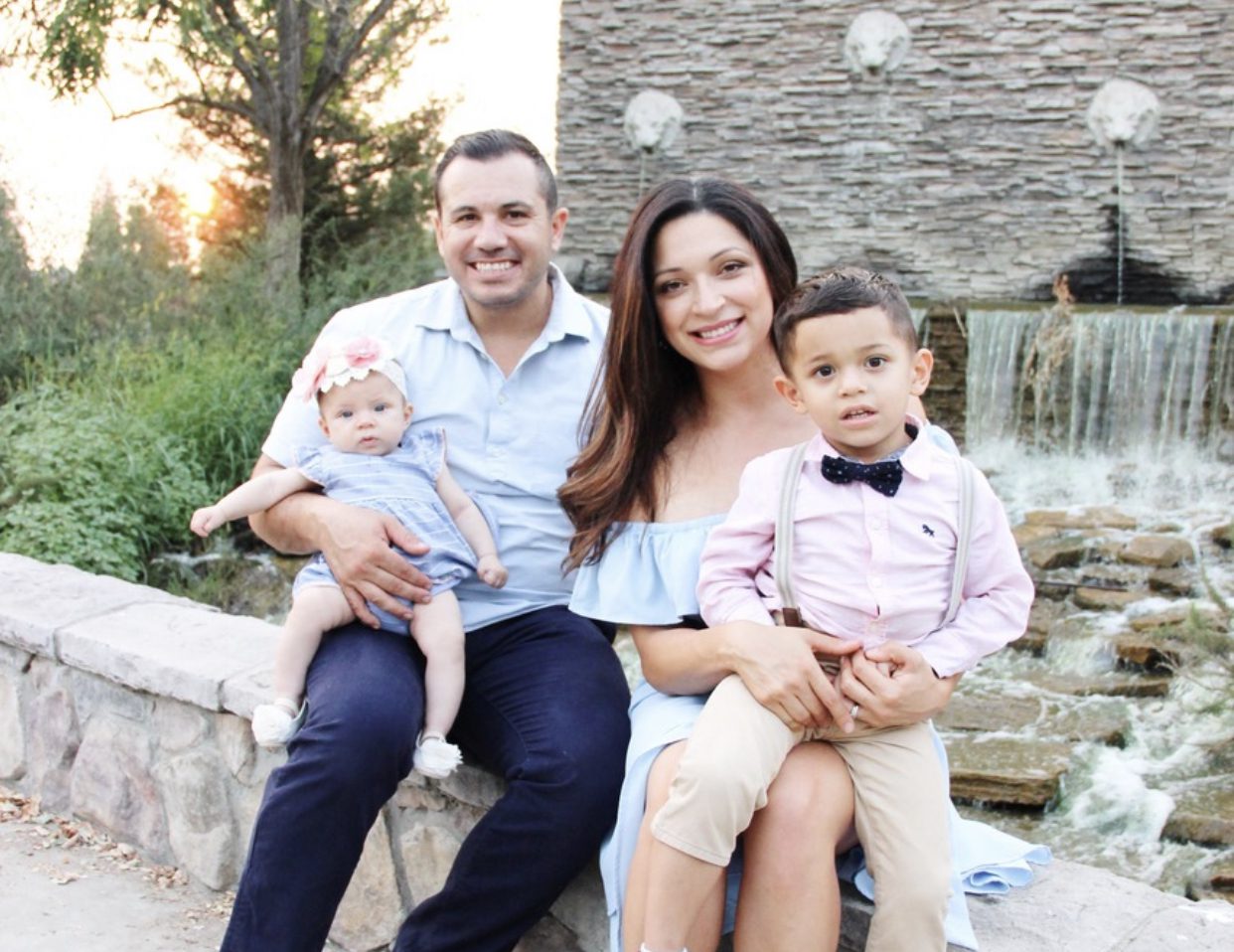 A family of four sitting outdoors beside a waterfall